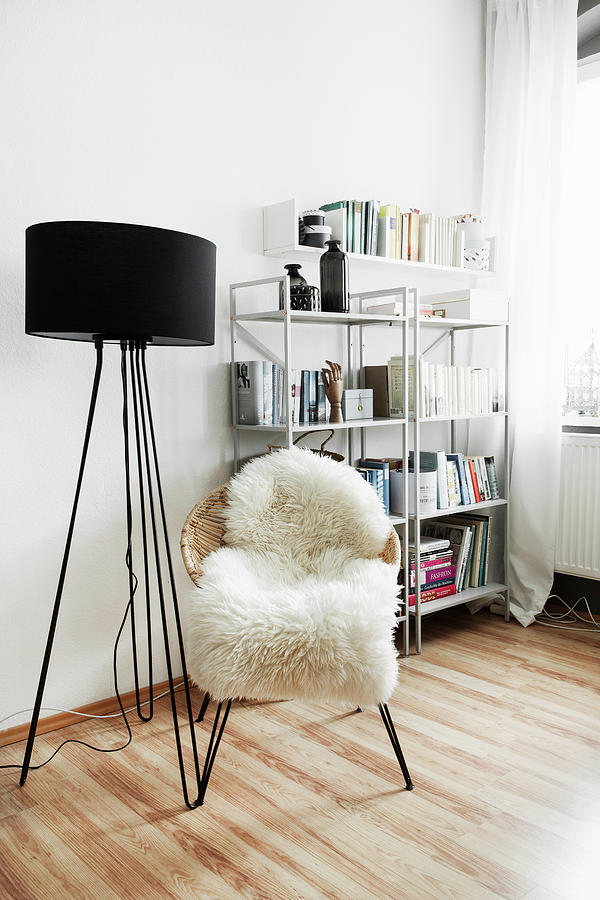 Black Standard Lamp And Easy Chair With Sheepskin Rug In Front Of Shelves Photograph by Hej.hem Interior