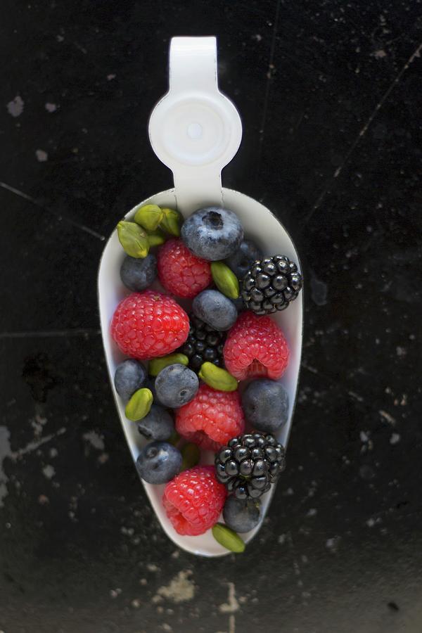 Blackberries, Raspberries, Blueberries And Pistachios On A White Enamel Spoon Photograph by Tina Engel