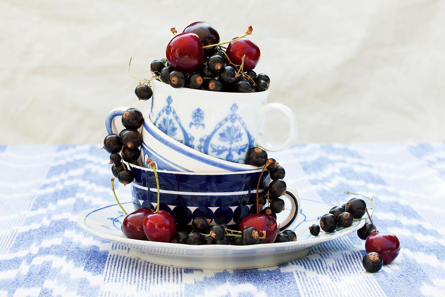 Blackcurrants And Cherries In Stacked Teacups Photograph by Sabine Lscher