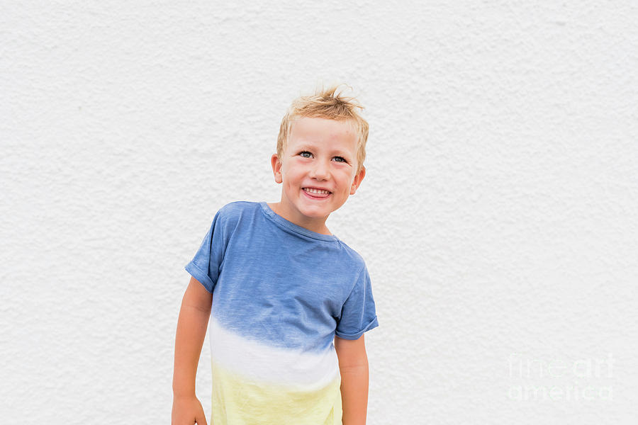 Blond boy making funny faces on white background. Photograph by Joaquin Corbalan