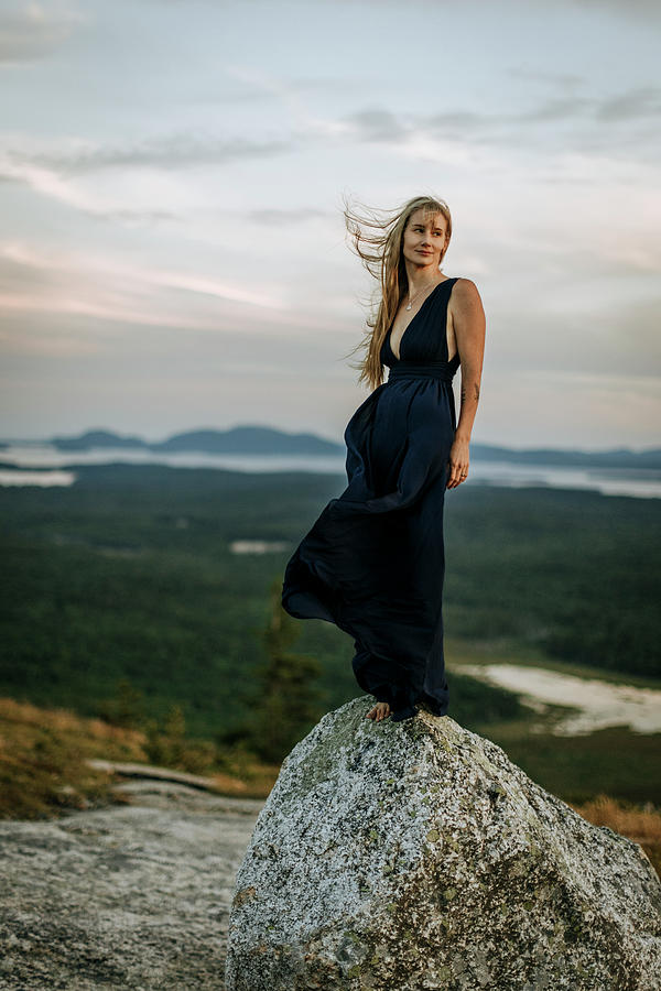 Nature Photograph - Blonde Woman In Long Dark Dress Stands On Rock. Windblown. by Cavan Images / Chris Bennett