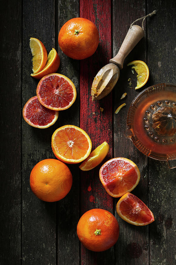 Blood Oranges Cut, Halved, Sliced And Juiced With Wooden Juicing Tool On Rustic Dark Wooden Background With Red Stripe Photograph by Stacy Grant