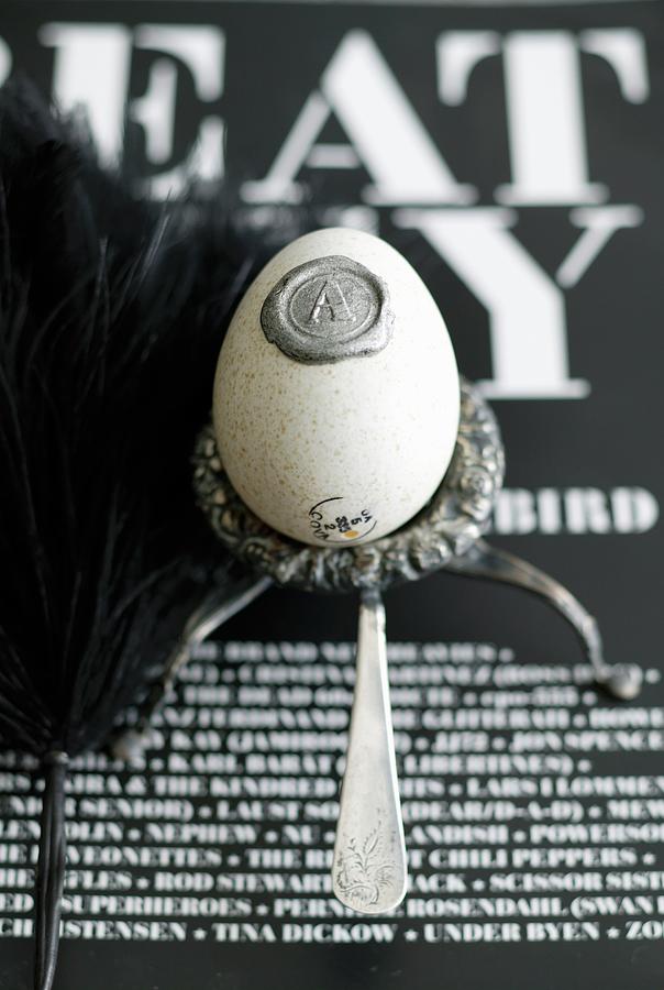 Blown Egg With Wax Seal In Silver Egg Cup On Black And White Lettered Surface Photograph by Bjarni B. Jacobsen