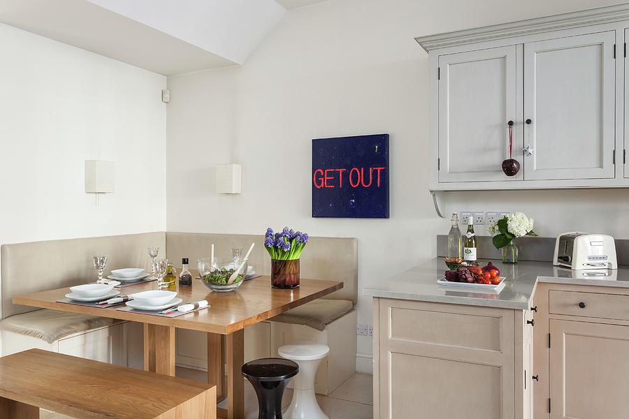 Blue-red Typeface Behind A Square Dining Table With Corner Bench And Simple Kitchen With Serene Shaker Style Color Scheme Photograph by Simon Maxwell Photography