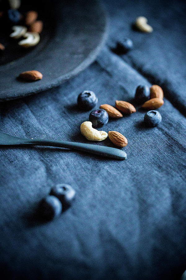 Blueberries, Almonds And Cashews On A Blue Tablecloth Photograph by Claudia Timmann