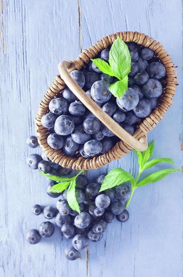 Blueberries In A Basket On A Blue Wooden Background Photograph by Barbara Pheby