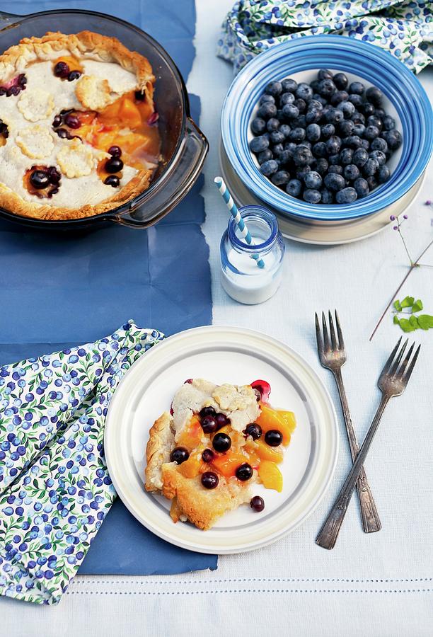 Blueberry And Peach Pie On A Plate And In Baking Dish; Bowl Of Fresh Blueberries; Bottle Of Milk With A Straw Photograph by Strokin, Yelena