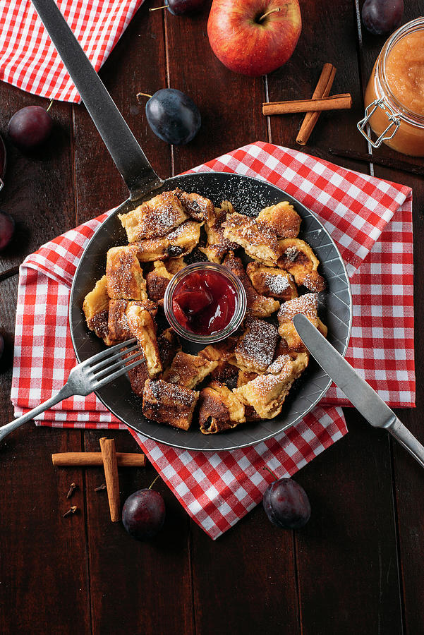 Bohemian Kaiserschmarrn With Applesauce And Roast Plums In A Cast-iron Pan On A Red And White Cloth Photograph by Christian Kutschka