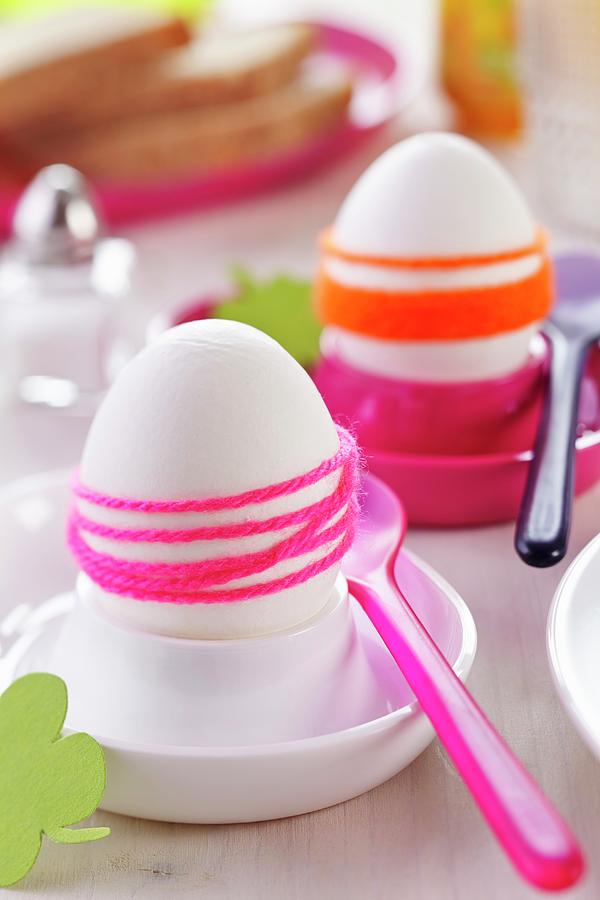 Boiled Eggs Wrapped In Brightly Coloured Woollen Yarn In Pink And White Eggcups With Plastic Spoons Photograph by Franziska Taube