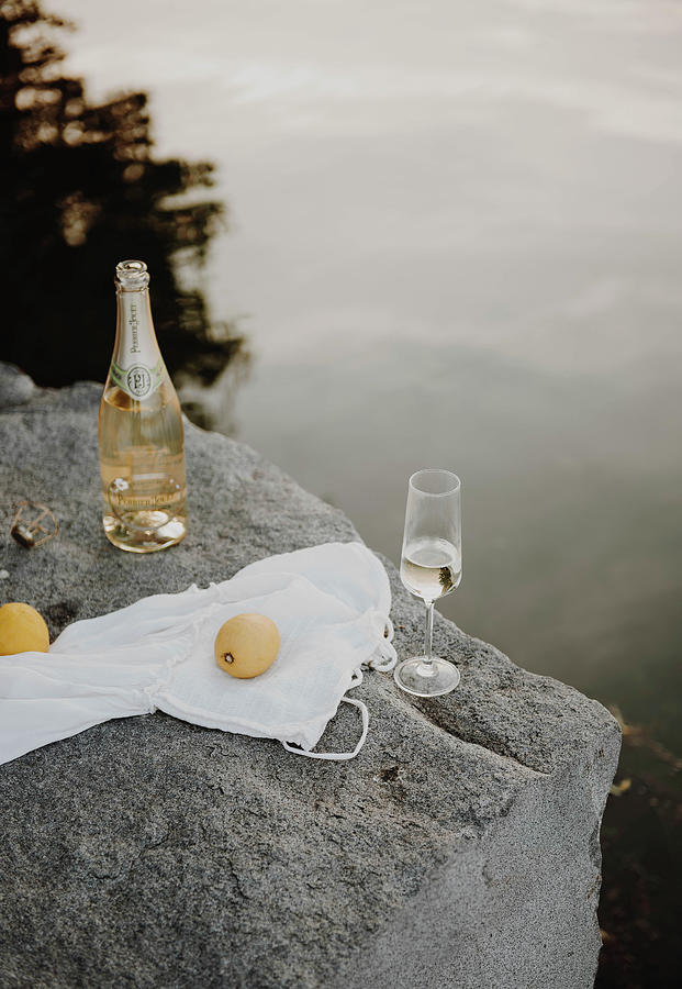 Bottle And Glass Of Sparkling Wine On Rocky Lake Shore Photograph by Agata Dimmich