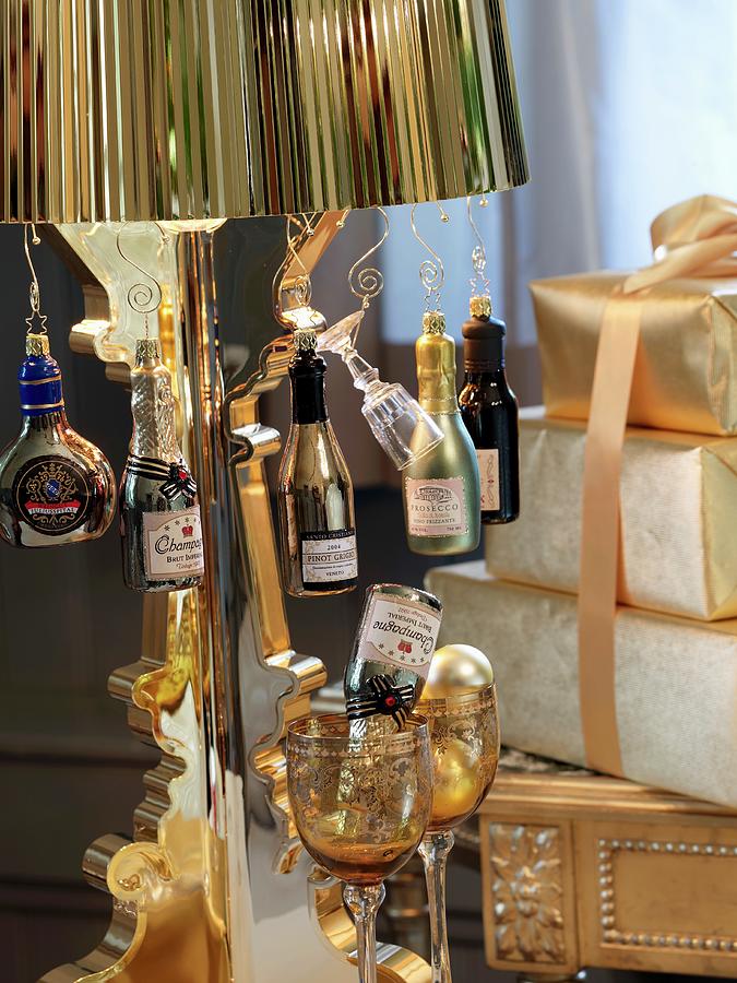 Bottle-shaped Ornaments Hanging From Brass Lampshade Of Standard Lamp Next To Stack Of Presents Photograph by Matteo Manduzio