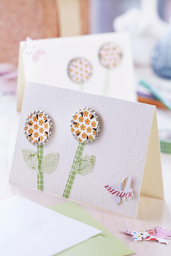 Bottle Tops Pressed Flat And Covered With Stickers As Flowers With Paper Stems And Paper Butterfly On Elegant White Greetings Card Photograph by Franziska Taube