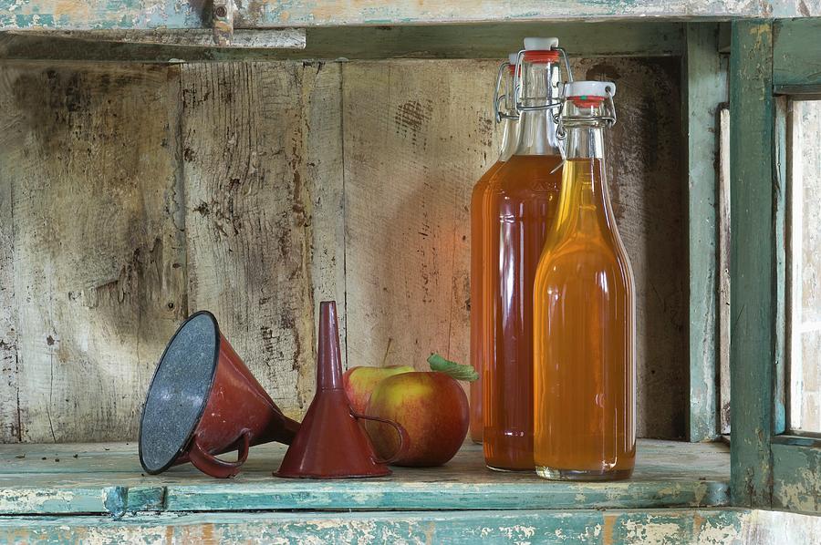 Bottles Of Apple Juice, A Funnel And Jonagold Apples On A Rustic Shelf