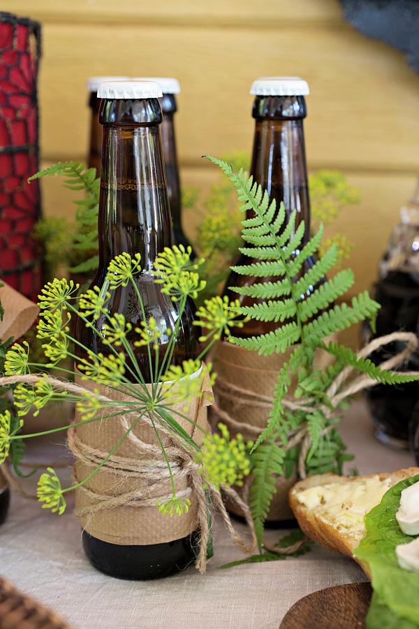 Bottles Of Beer Wrapped In Paper And Decorated With Dill Flowers And Ferns On Dresser Photograph by Cecilia Mller