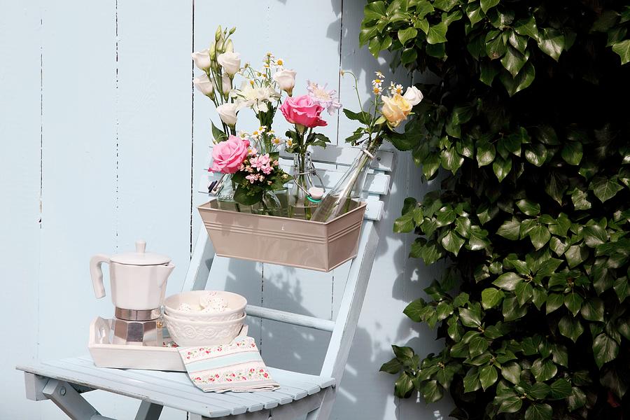Bottles Of Flowers In Window Box On Wooden Chair Against White Wooden Wall Photograph by Thordis Rggeberg