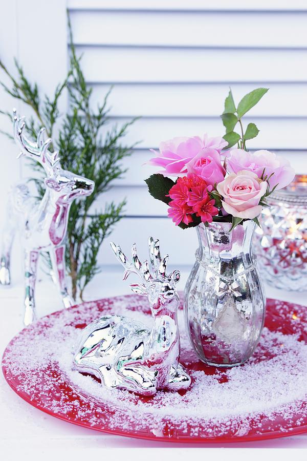 Bouquet Of Roses In Mercury Glass Vase And Deer Ornament In Artificial Snow On Red Plate Photograph by Angelica Linnhoff