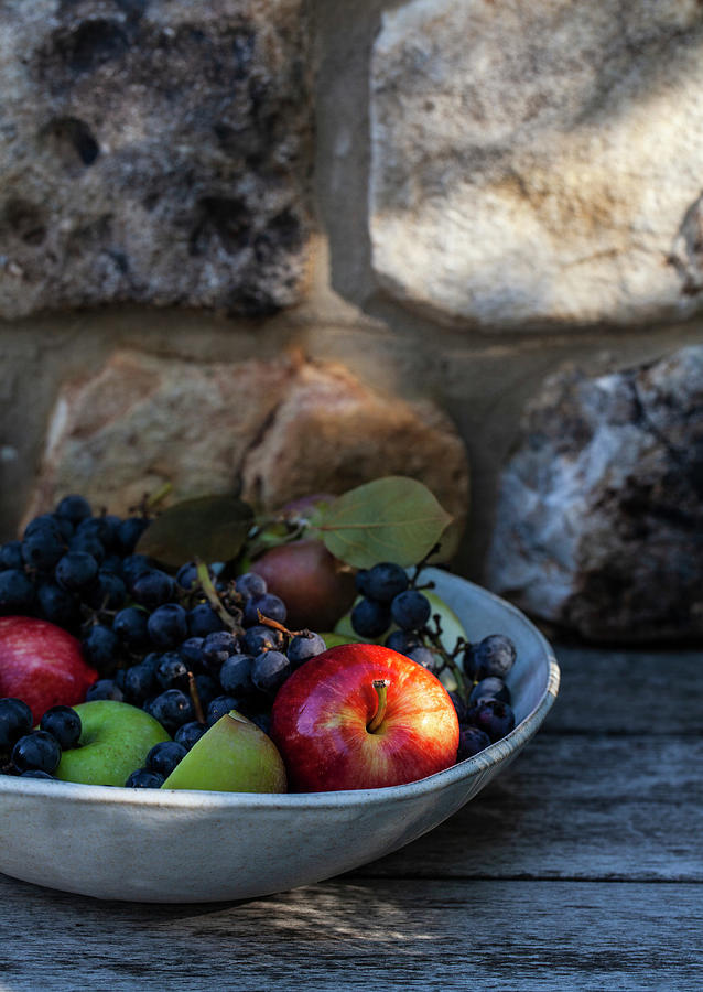 Bowl Of Apples With Leaves And Concord Grapes, Outside With A Stone Surface Behind Photograph by Ryla Campbell