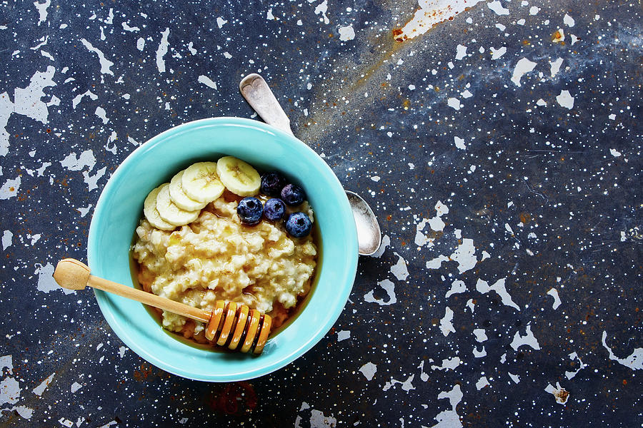 Bowl Of Classic Oatmeal Porridge With Honey, Banana And Organic Frozen Blueberries Photograph by Yuliya Gontar