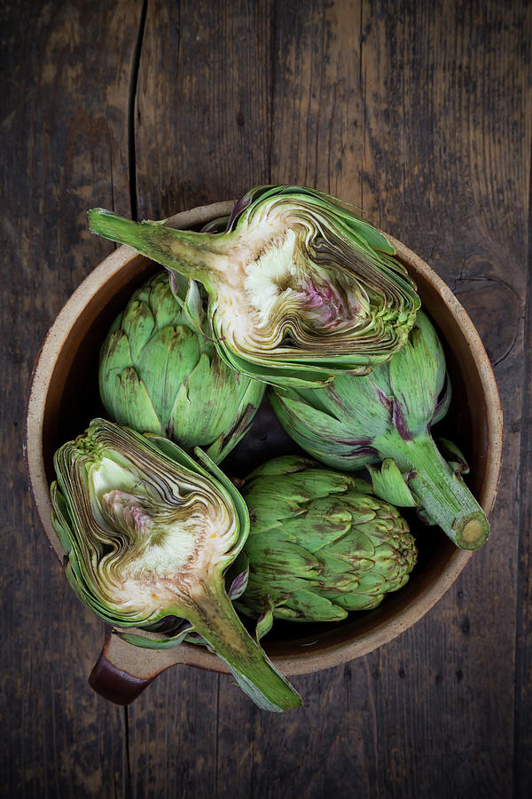 Bowl Of Organic Artichokes On Wooden Photograph by Westend61