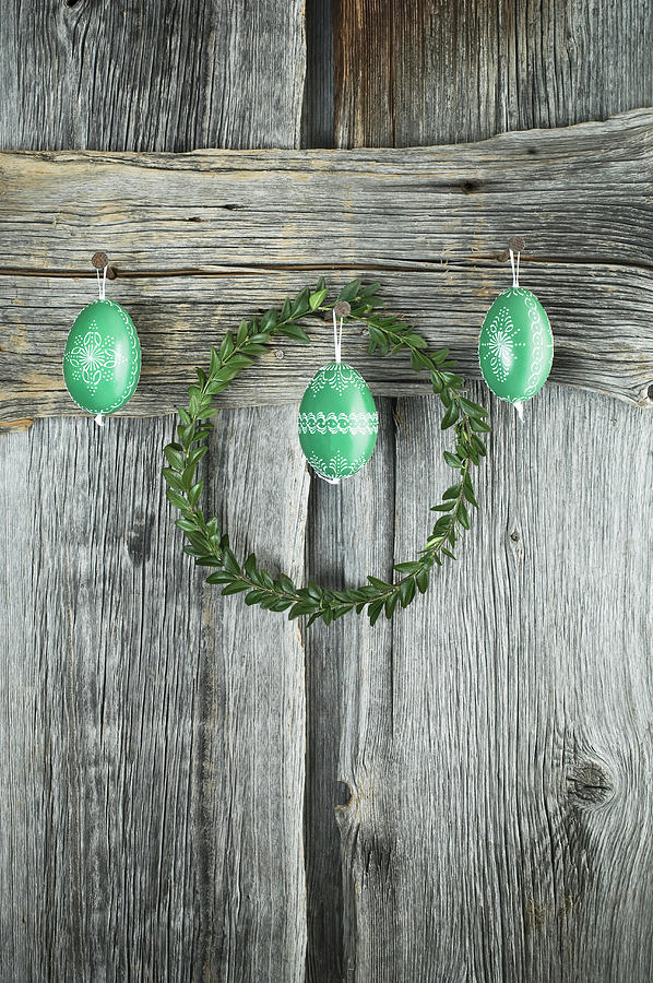 Box Wreath And Hand-painted Green Easter Eggs On Rustic Wooden Wall Photograph by Achim Sass