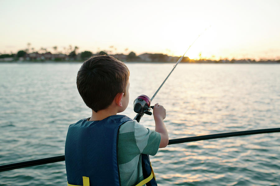 Boy Fishing In Sea While Standing On Boat Photograph by Cavan Images ...