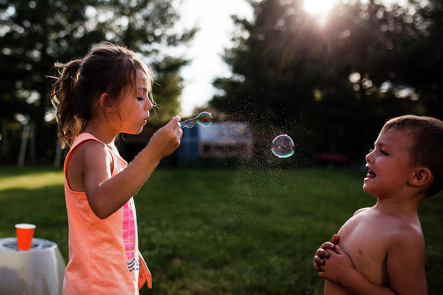 Boy Looking At Sister Blowing Bubble At Backyard Photograph by Cavan ...