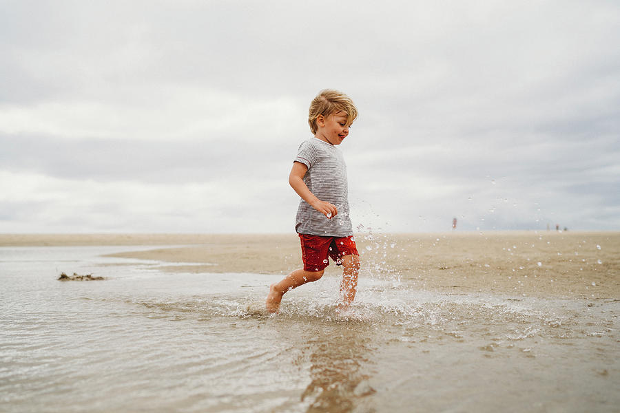 Boy Running Splashing Water At Fuerteventura Beach On Overcast Day ...