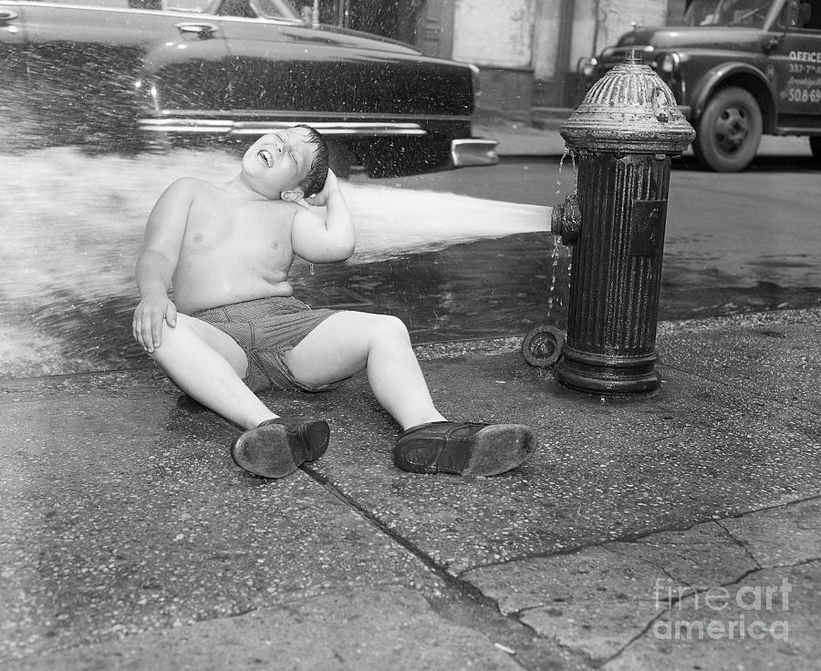 Boy Sits On Sidewalk In Fire Hydrant Photograph by Bettmann