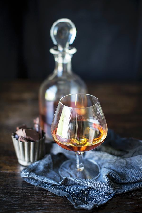 Brandy In A Glass And The Carafe With Chocolate Pralines Photograph by Helen Cathcart