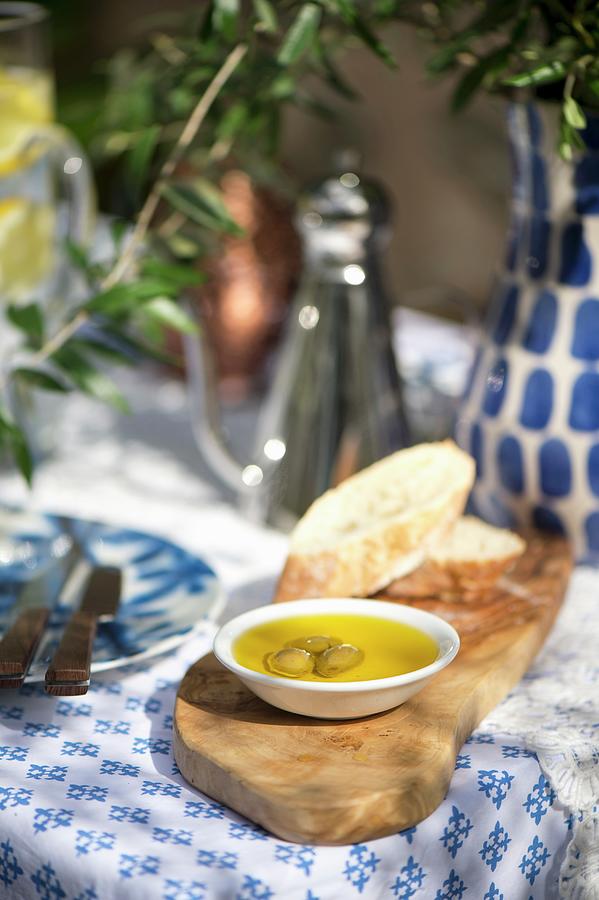 Bread, Oil And Olives On Wooden Board On Set, Mediterranean Table Photograph by Winfried Heinze
