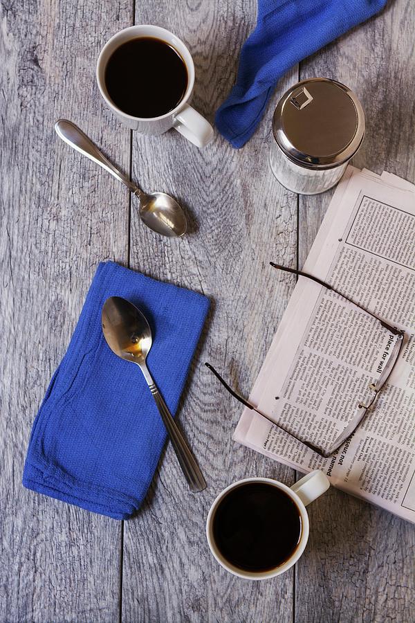 Breakfast For Two With Coffee Cups, Spoons, Napkins, A Sugar Pot, A Morning Newspaper And A Pair Of Glasses Photograph by Brian Enright