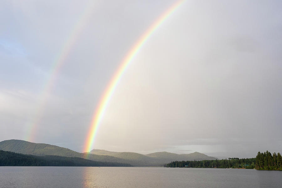 Sunset Photograph - Bright Double Rainbow Over Calm Lake And Forest Covered Hillside by Cavan Images