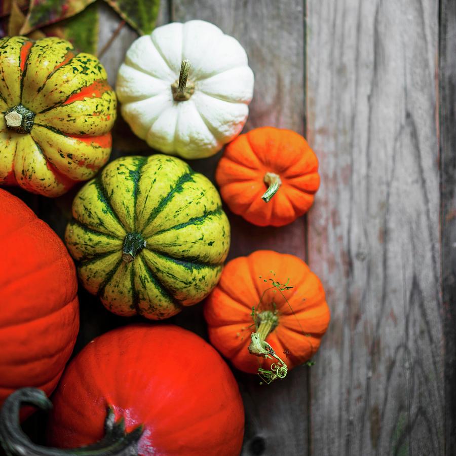 Bright Pumpkins And Autumn Leaves On Rustic Wooden Surface Photograph by Alena Haurylik