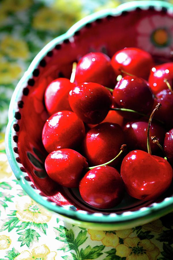Bright Red Cherries In A Colourful Ceramic Bowl Photograph by Fabrizia Postiglione