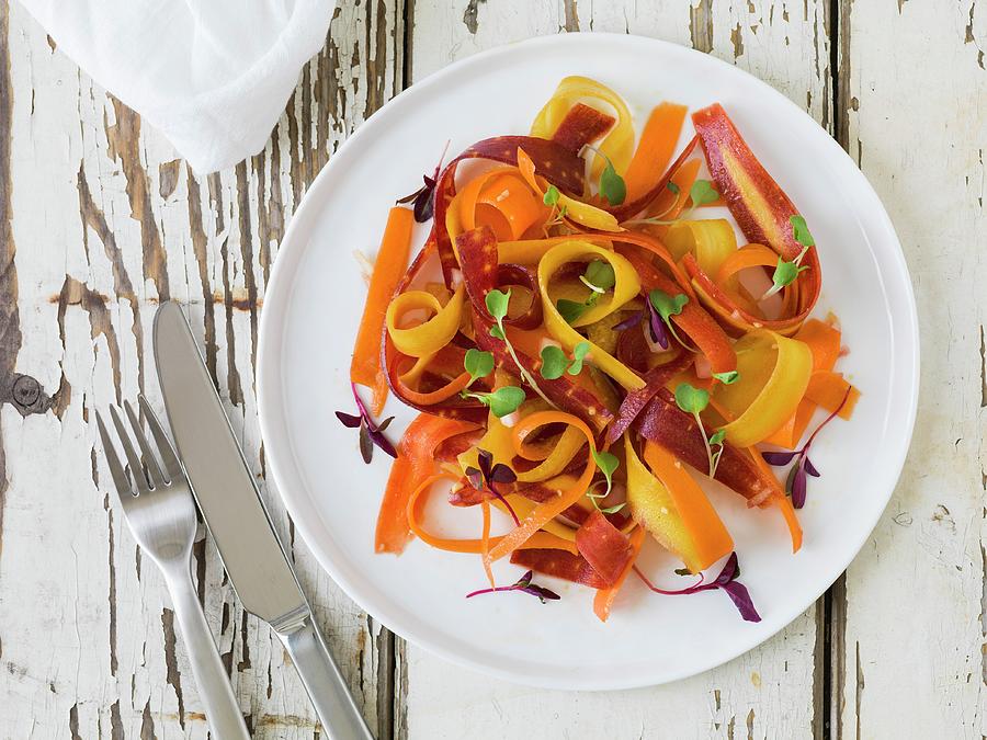 Bright Yellow, Orange And Red Carrot Salad With Micro-greens On A White Plate Sitting On An Antique White Wood Surface Photograph by Don Crossland