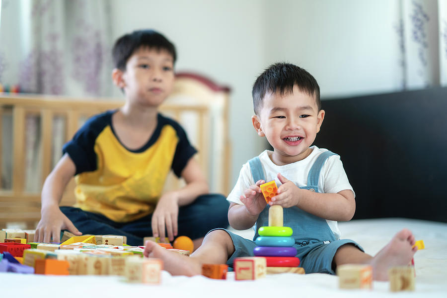 Brother and a smile boy play a toy togather on the bed Photograph by Anek Suwannaphoom