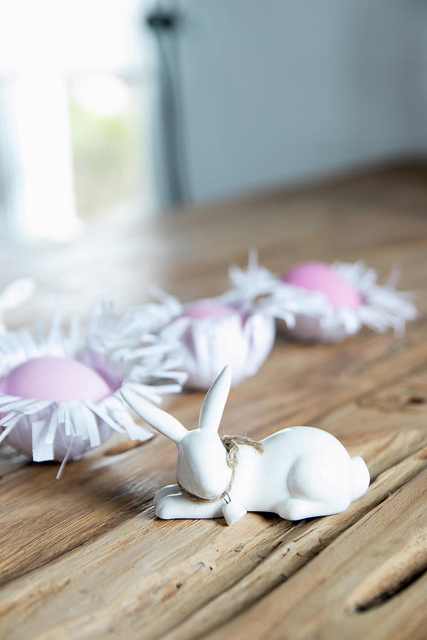 Bunny Figurines And Easter Eggs In Handmade Paper Nests On Wooden Surface Photograph by Astrid Algermissen