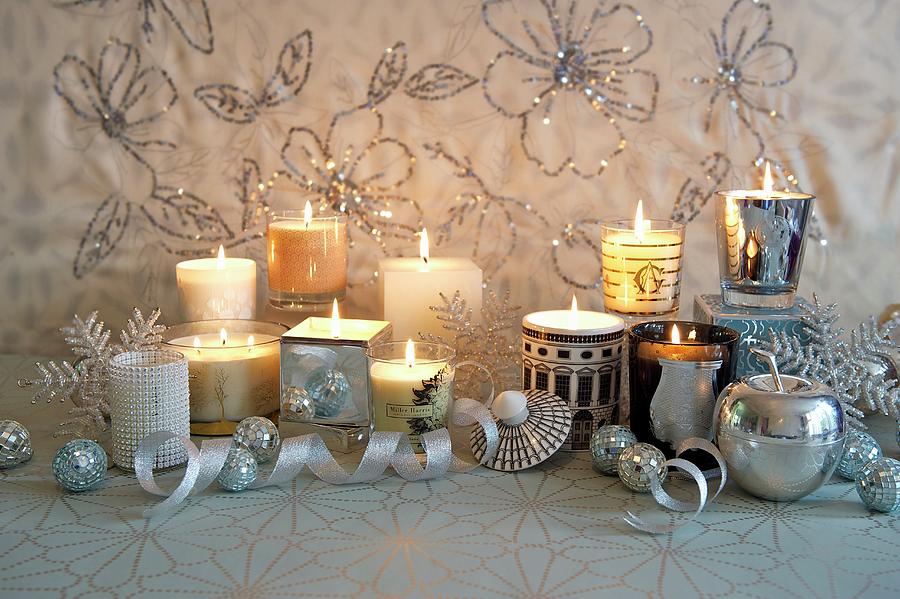 Burning Candles In Various Glass Containers On A Festively Decorated Shelf Photograph by Winfried Heinze