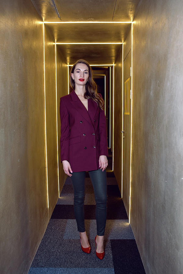 business girl in a Burgundy jacket and red shoes standing in the hallway Photograph