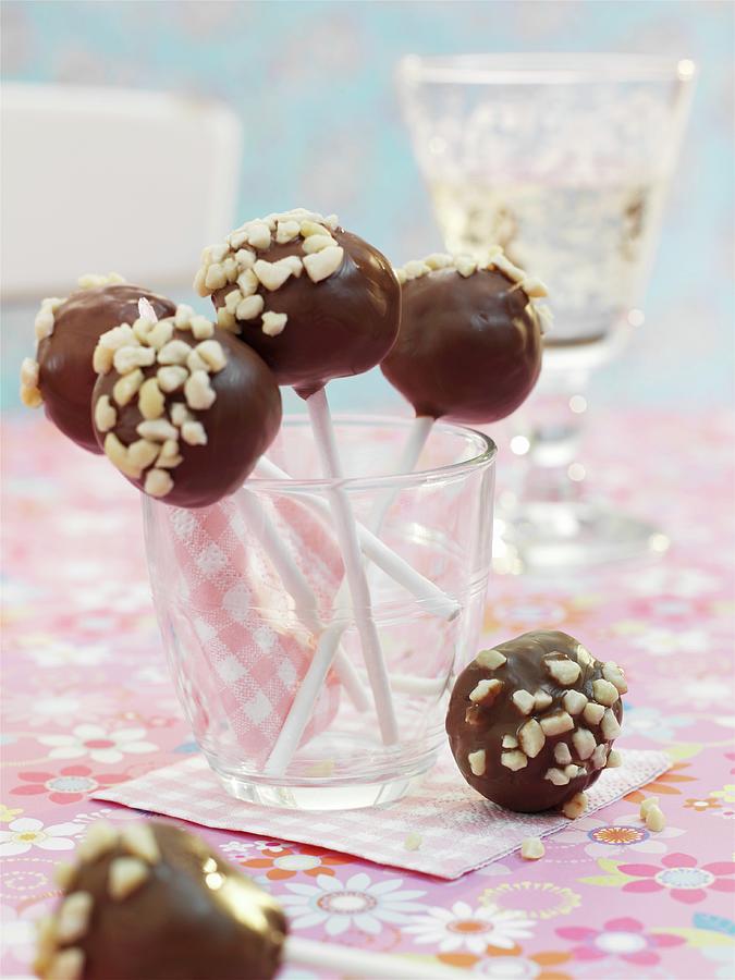 Cake Pops With Chocolate Glaze And Chopped Nuts Photograph by Garlick, Ian