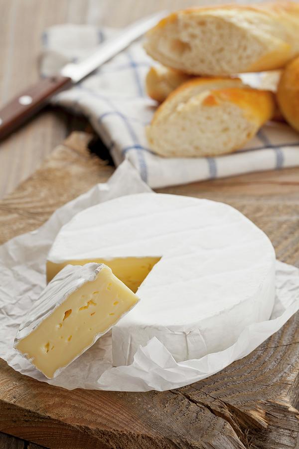 Camembert, One Slice Cut, On A Wooden Platter With Chunks Of Baguette Photograph by Shawn Hempel