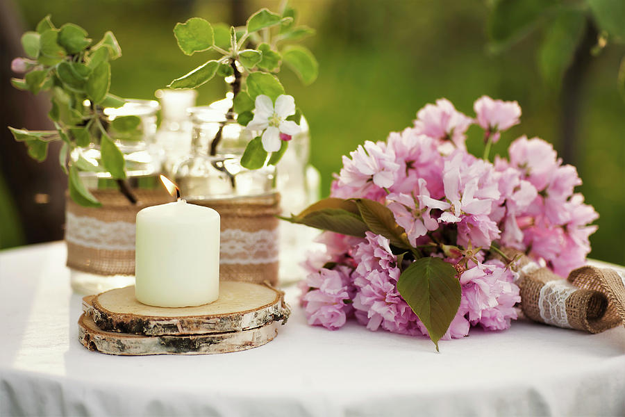 Candle On Wooden Coaster, Cherry Blossom And Peonies On Garden Table Photograph by Alicja Koll