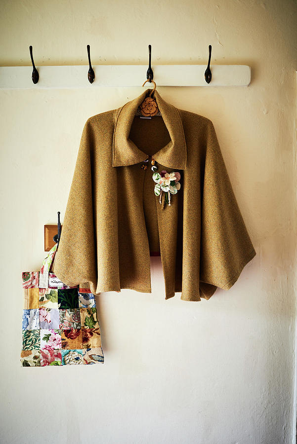 Cape With Floral Brooch Hung From Coat Rack Photograph by Catherine Gratwicke