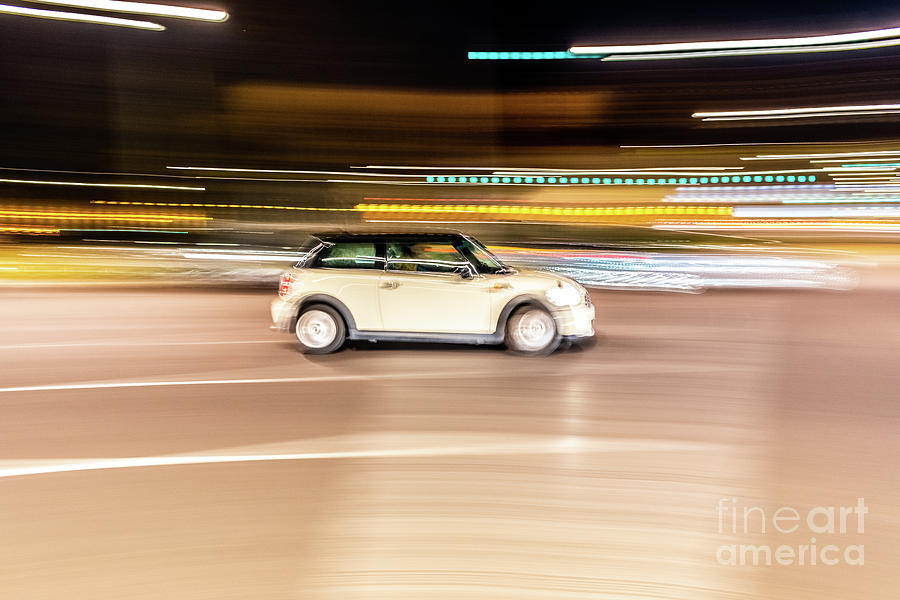 Car rolling at full speed through the city at night, image of panning, with defocused background lights. Photograph by Joaquin Corbalan