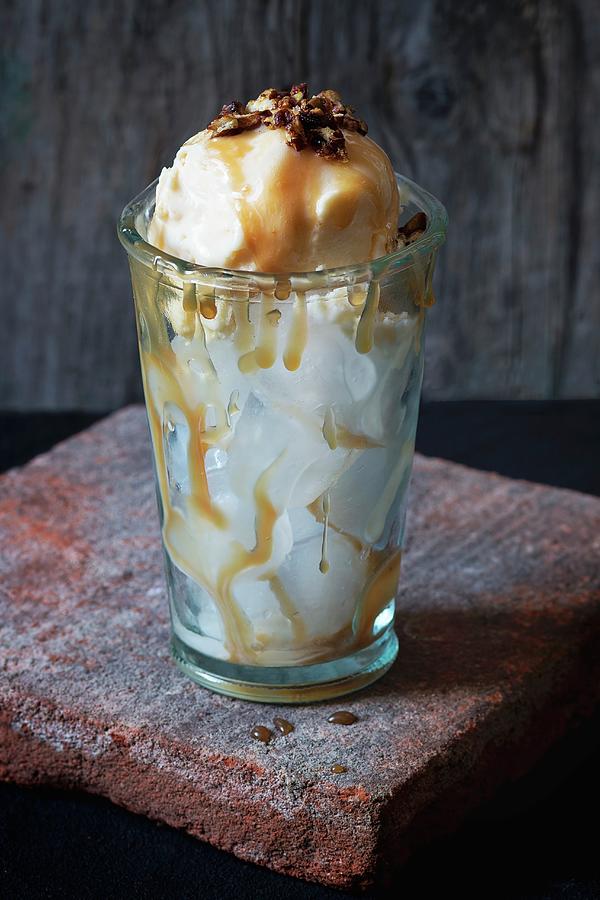 Caramel And Hazelnut Butter Ice Cream With Caramel Sauce And Crispy Nuts In A Glass With Ice Cubes Photograph by Natasha Breen