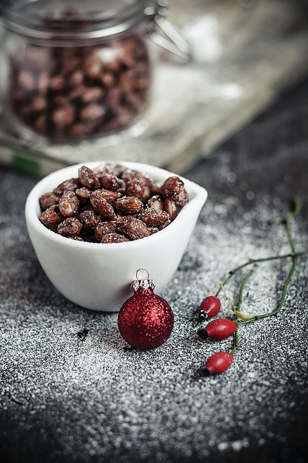 Caramelised Almonds In A White Bowl With Christmas Decoration Photograph by Susan Brooks-dammann