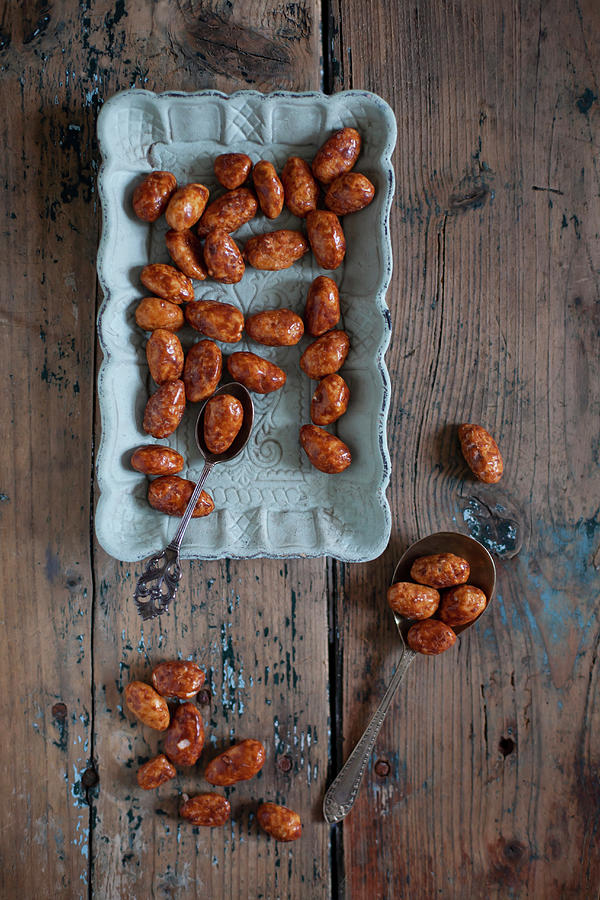 Caramelised Nuts On Blue Plate And Wooden Table Photograph by Alicja Koll