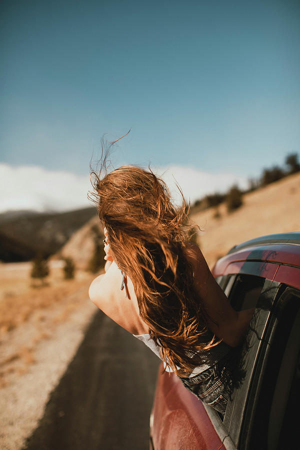 Carefree Young Woman With Tousled Hair Leaning Out From Car Window ...