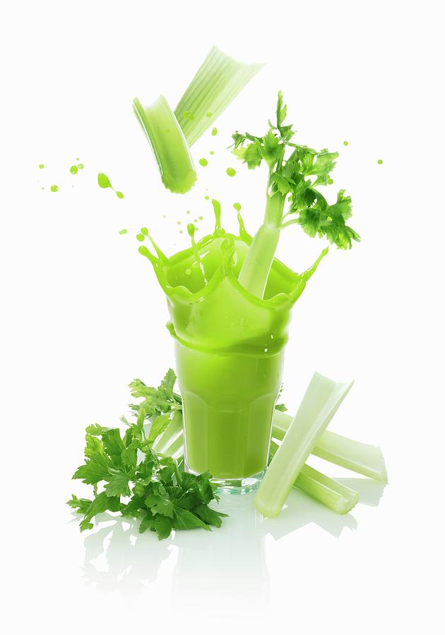 Celery Sticks Falling Into A Vegetable Drink Photograph by Krger & Gross