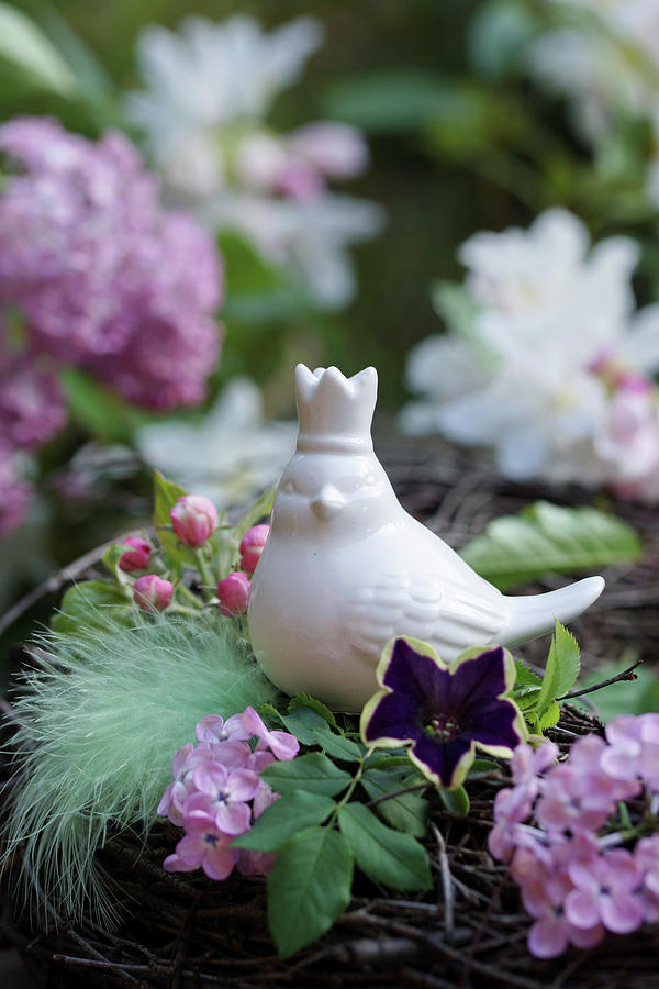 Ceramic Bird Amongst Lilac Flowers, Petunias, Apple Blossom And Feather Photograph by Angelica Linnhoff